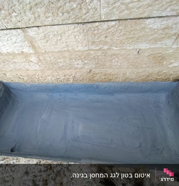 משטח אטום באיטום אפור ליד קיר אבן